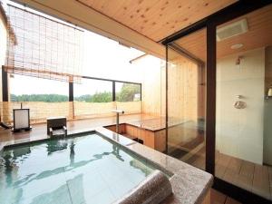 飛騨の山並みと町並みを一望する客室露天風呂（石風呂の例）
