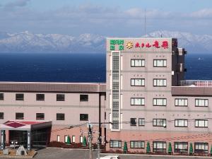 冬のホテル外観。背景の荒々しい冬の海と雪化粧の道南の山並みは壮観です。