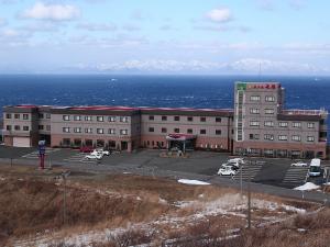 冬のホテル外観。背景に荒々しい冬の海と雪化粧の道南の山並み