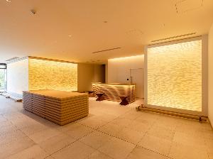 優しいオレンジの光で皆さまをお出迎えするフロント。壁紙には津島織物製造株式会社の紙布を使用しています。