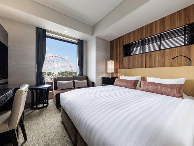 【観覧車側コーナーダブルルーム 22.2平米/ベッド幅160cm】シティビューを望むコーナーダブルはクイーンサイズのベッドと旅の疲れを癒すくつろぎのビューバス、独立した洗面・バスルームをご用意