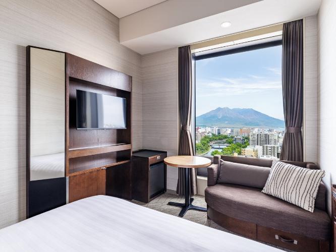 【桜島側ダブルルーム 17.7平米/ベッド幅150cm】雄大な桜島を望むことができるダブルルームは、くつろぎのソファスペースとナチュラルでやさしいデザインにこだわりました。